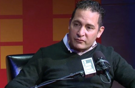 Boaz Gilad speaking into a microphone during a podcast interview
